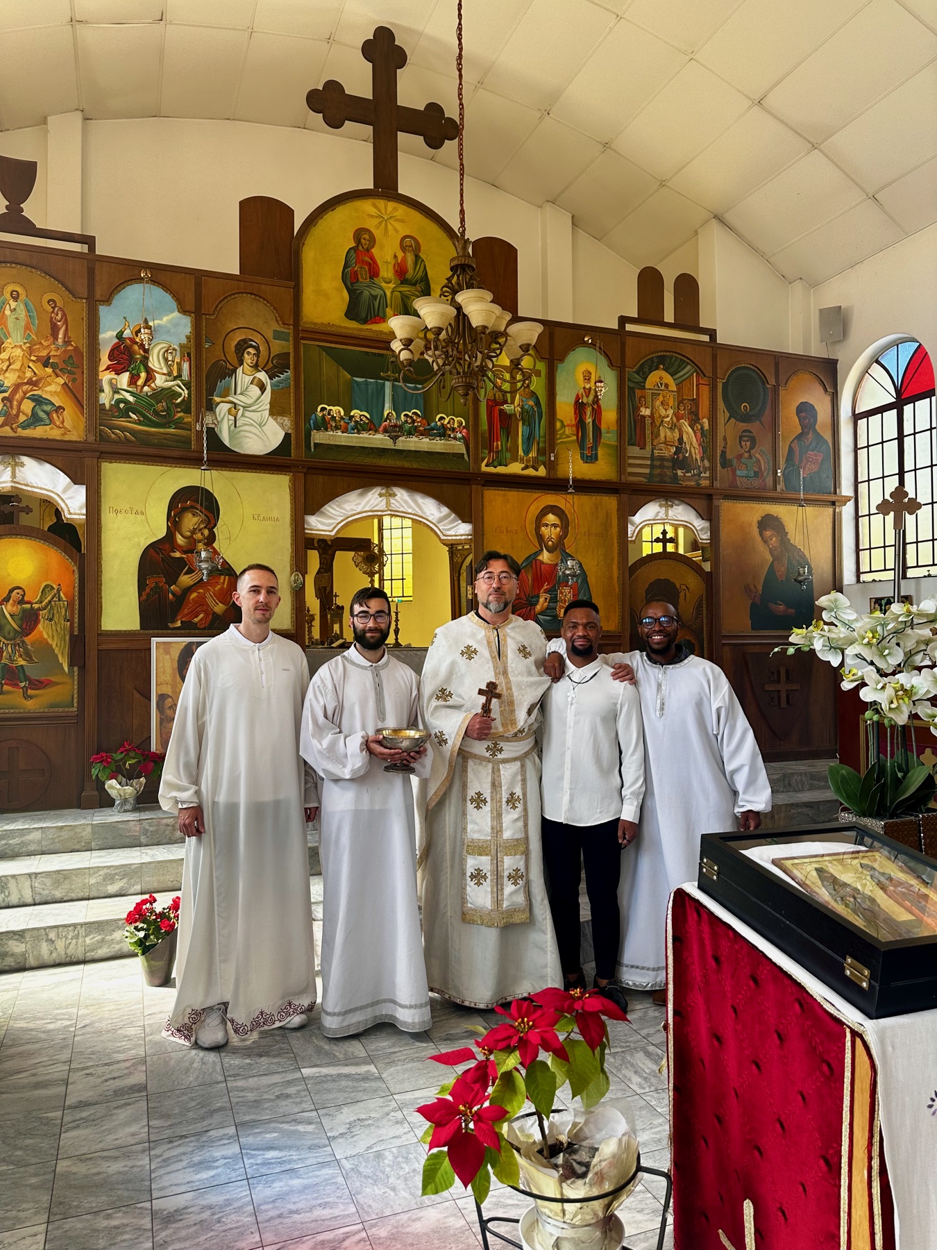Father Isajlo performing a baptism, assisted by young altar servers