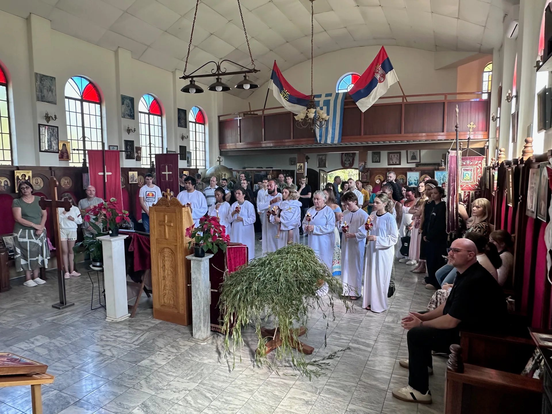 Children and parishioners gathered with baptismal candles during a Palm Sunday group baptism at St Thomas Serbian Orthodox Church