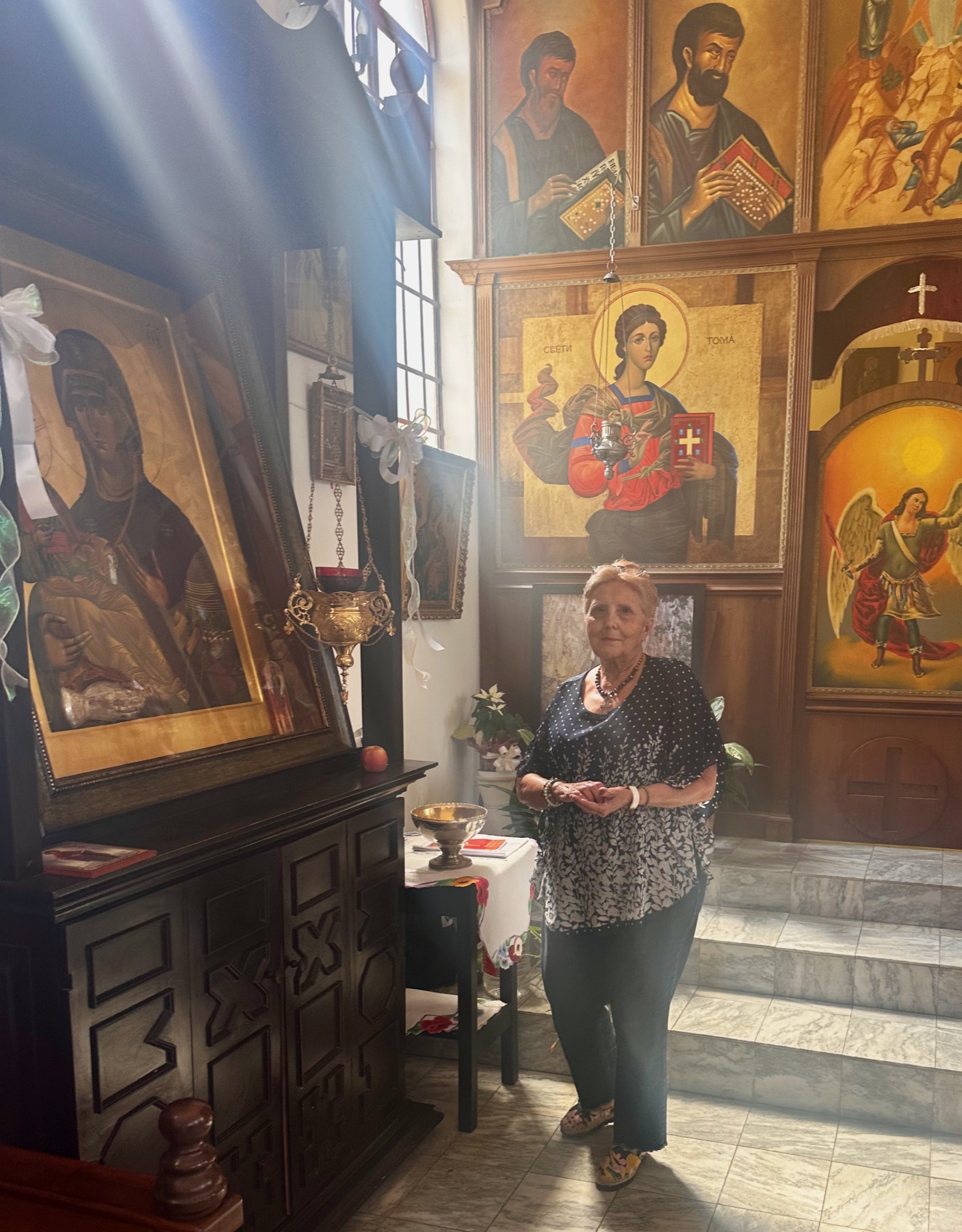A parishioner lighting a candle and praying before the icons